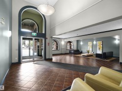 Spacious foyer featuring a grand arched doorway with glass entry doors, high ceilings, tile flooring, wall sconces, and recessed lighting - 