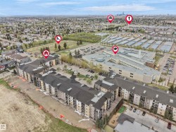 Multi-story residential buildings with balconies, featuring a large parking area and adjacent green space - 