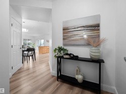 Welcoming entryway featuring light wood-finish flooring, white baseboards, and a contemporary console table - 