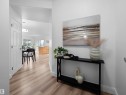 Welcoming entryway featuring light wood-finish flooring, white baseboards, and a contemporary console table - 104 14612 125 Street, Edmonton, AB 