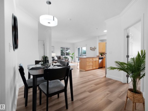 Open-concept living space featuring wood-finish flooring, white walls, and crown molding - 104 14612 125 Street, Edmonton, AB 