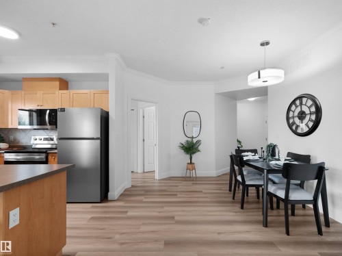 Open-concept kitchen and dining area featuring wood-finish flooring - 104 14612 125 Street, Edmonton, AB 