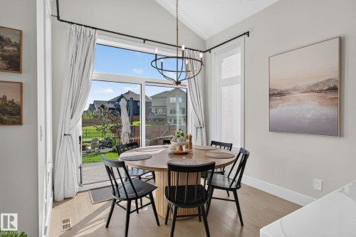 Dining area featuring wood-finish flooring, a circular wood table, and a contemporary chandelier - 14 Jane Point(E), St. Albert, AB 