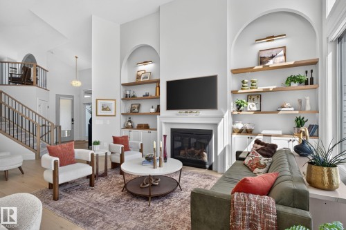 Living room featuring a fireplace with a white mantel, built-in shelving, high ceilings, and wood-finish flooring - 14 Jane Point(E), St. Albert, AB 