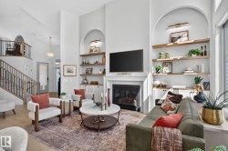 Living room featuring a fireplace with a white mantel, built-in shelving, high ceilings, and wood-finish flooring - 