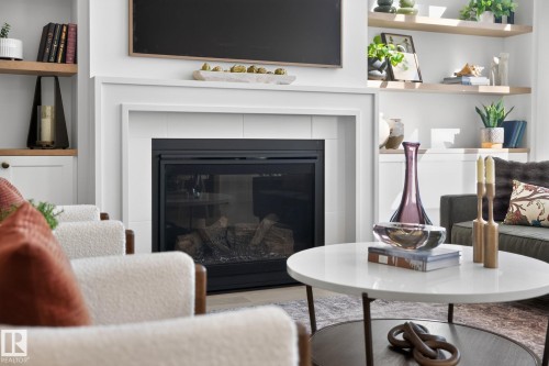 Modern fireplace featuring a white mantel, black firebox, and a visible log set - 14 Jane Point(E), St. Albert, AB 