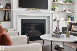 Modern fireplace featuring a white mantel, black firebox, and a visible log set - 