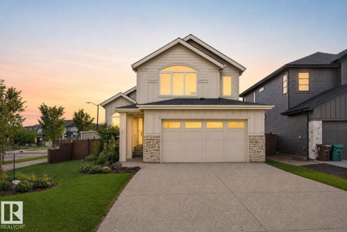 Two-story residence featuring a two-car garage, stone accents, arched window, and a concrete driveway - 14 Jane Point(E), St. Albert, AB 