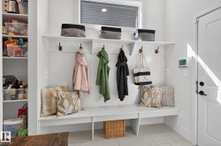 Mudroom with built-in bench seating, upper shelving, and coat hooks - 
