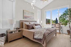 Vaulted ceiling bedroom featuring light wood-finish flooring, a contemporary chandelier, large picture windows, and roller shades - 