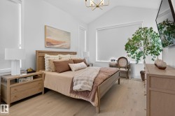 Bedroom featuring vaulted ceilings, light wood-finish flooring, and multiple windows with roller shades - 
