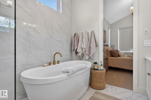 Freestanding soaking tub with gold-finish fixtures and floor-to-ceiling marbled tile surround - 14 Jane Point(E), St. Albert, AB 