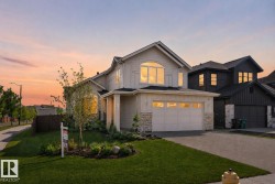 Contemporary two-story residence featuring a light-toned facade with stone accents, an attached two-car garage, manicured front lawn, and a paved driveway - 