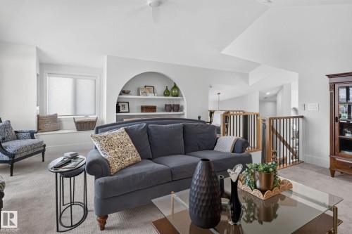 Carpeted living area featuring a built-in arched shelving unit, a window seat with roller shades, and a ceiling fan - 14 Jane Point(E), St. Albert, AB 