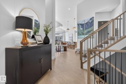 Entryway featuring light wood-finish flooring, a contemporary staircase with wood handrails and black balusters, and recessed lighting - 