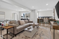 Open-concept living area with light wood-finish flooring, recessed lighting, and an arched doorway - 