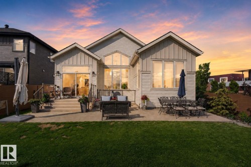 Rear exterior featuring a spacious concrete patio, direct lawn access, multiple large windows, and sliding glass door - 14 Jane Point(E), St. Albert, AB 
