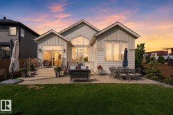 Rear exterior featuring a spacious concrete patio, direct lawn access, multiple large windows, and sliding glass door - 