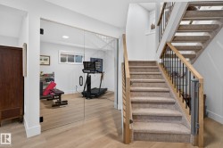 Carpeted staircase with light wood handrails and black metal balusters - 