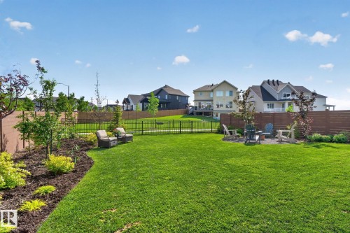 Expansive backyard featuring a lush lawn, a dedicated fire pit area, and landscaped garden beds with mature plantings - 14 Jane Point(E), St. Albert, AB 