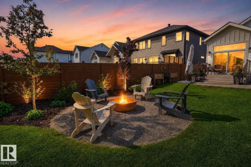 Backyard fire pit area featuring a gravel patio, built-in fire pit, and surrounding landscaping - 14 Jane Point(E), St. Albert, AB 