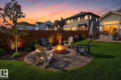 Backyard fire pit area featuring a gravel patio, built-in fire pit, and surrounding landscaping - 