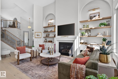 Living area featuring a fireplace with a mantel, built-in shelving, and wood-finish flooring - 14 Jane Point(E), St. Albert, AB 