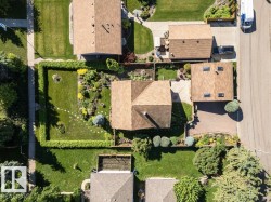 Aerial perspective showcasing a property with a gabled roof, established landscaping, and a manicured lawn - 