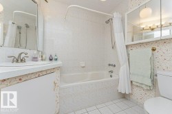 Bathroom featuring a white bathtub, ceramic tile surround, and a coordinating tiled floor - 