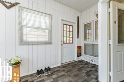 Enclosed porch featuring a paneled white ceiling, white vertical plank walls, and multi-tone tile flooring - 
