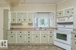 Kitchen featuring light green cabinetry with decorative hardware, a bay window, a built-in microwave, an electric range, and laminate countertops - 