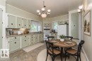 Kitchen with light green cabinetry, integrated appliances, stone-finish countertops, and a tile floor - 4 Jubilee Drive, Fort Saskatchewan, AB 