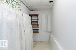 White privacy curtain on a rod, wood shelving system, white panel door, and tile flooring - 