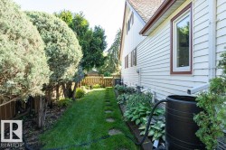 Side yard featuring a stone pathway, manicured lawn, established trees, and perimeter fencing - 