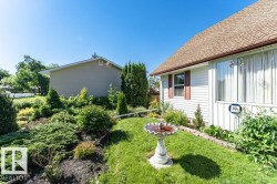 Manicured front yard with diverse plantings, a classic birdbath, and a well-maintained lawn - 