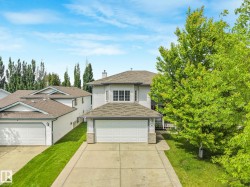 Two-story residence featuring light-colored siding, a detached garage, and a concrete driveway - 