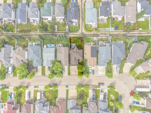 Aerial view showcasing a residential property with a multi-gabled roofline, a private rear yard with mature trees, and an asphalt driveway - 98 Bridgeport Wynd, Leduc, AB 