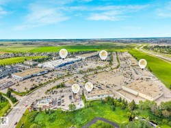Expansive commercial area featuring multiple retail buildings and extensive parking facilities, bordered by arterial roads and open green spaces - 