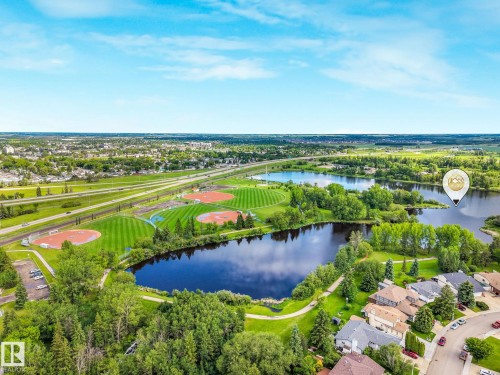 Aerial perspective showcasing a residential area bordered by a large body of water, extensive green spaces, and multiple sports fields - 98 Bridgeport Wynd, Leduc, AB 