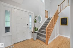 Light wood-finish flooring complements the entrance, featuring a paneled door with sidelight windows - 
