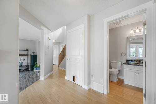 Bright hallway featuring wood-finish flooring, white trim, and light gray wall paint - 98 Bridgeport Wynd, Leduc, AB 