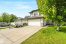Two-story residence featuring light-colored siding, an attached garage with a white door, and a concrete driveway - 98 Bridgeport Wynd, Leduc, AB 
