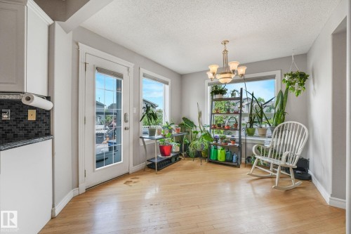 Dining area with wood-finish flooring and a multi-light chandelier - 98 Bridgeport Wynd, Leduc, AB 