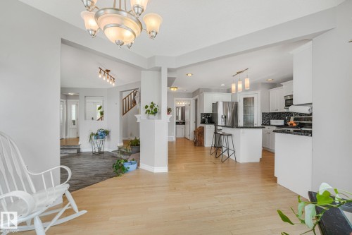 Bright interior featuring light wood-finish flooring and a central chandelier - 98 Bridgeport Wynd, Leduc, AB 