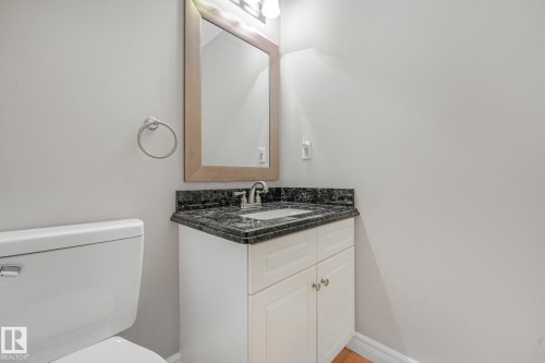 White vanity with dark granite countertop, undermount sink, and chrome faucet - 98 Bridgeport Wynd, Leduc, AB 