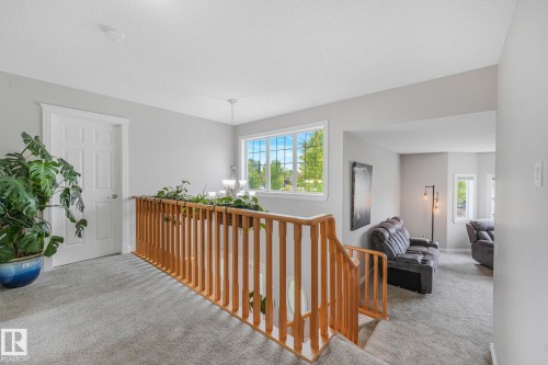 Upper-level landing featuring light gray carpeting and a light wood-finish stair railing - 98 Bridgeport Wynd, Leduc, AB 