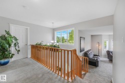 Upper-level landing featuring light gray carpeting and a light wood-finish stair railing - 