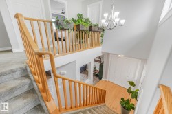 Multi-level interior featuring a carpeted stairway with natural wood railings, leading to a lower level with wood-finish flooring - 