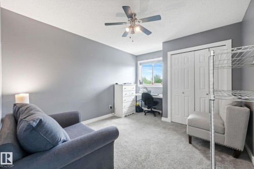 Bedroom featuring neutral gray walls, light gray carpet, and a ceiling fan with integrated lighting - 98 Bridgeport Wynd, Leduc, AB 