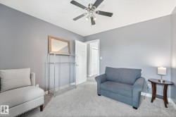Room featuring light gray walls, textured carpet, a white paneled door, and a ceiling fan with integrated lighting - 